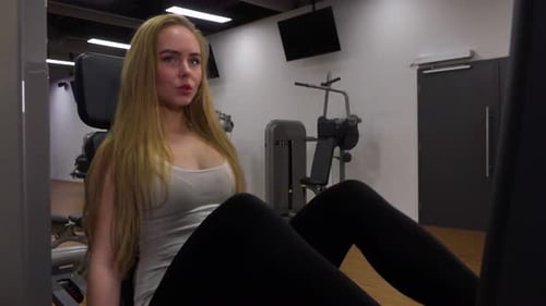 A Young Beautiful Woman Trains on a Leg Press Machine in a Gym - Closeup