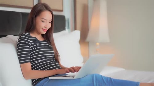 Woman Uses Laptop Computer While Sitting on Bed