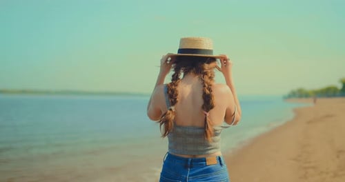 Woman Strolls Along Sandy Beach on Sunny Day