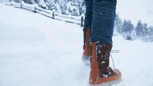 Close Up View on Red Brown Snow Boots Walking By Fresh White Snow in Countryside