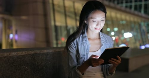 Woman Using Tablet at Night in the City