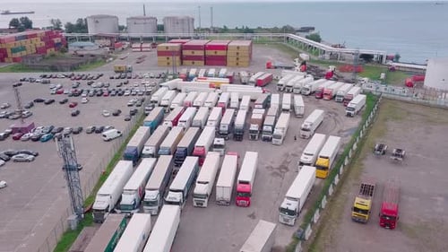 Shooting from a drone to a truck parking lot. Many trucks are parked at port,