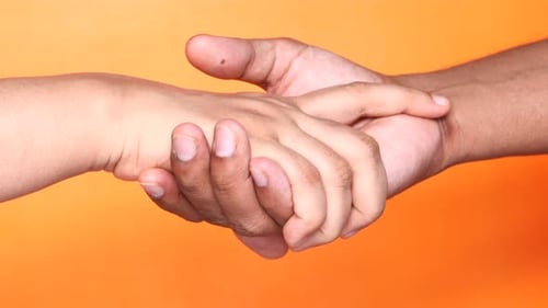 Close Up of Couple Holding Hands Against Orange Background.