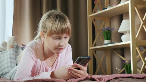 Child Lies on Bed Using Smartphone