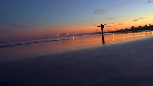 Man making the plane by the beach in a beautiful light at dawn, feeling alive, freedom and enjoying