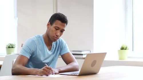 Young Adult Works at Table in Bright Office