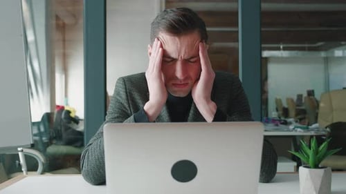 Stressed man working at a computer in office