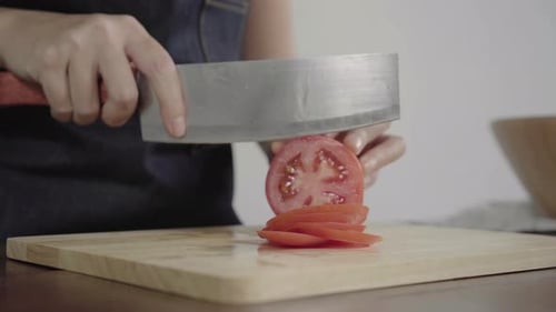 woman making salad healthy food and chopping tomato on cutting board in the kitchen.