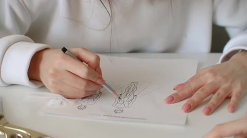 Designer sketching fashion figures on paper with pencil