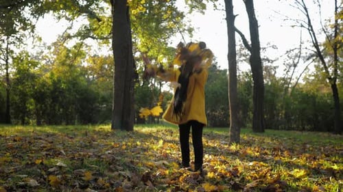 Young Girl Plays With Leaves in Autumn Park