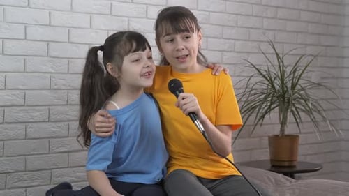 Two Girls Singing Together with Microphone in Room