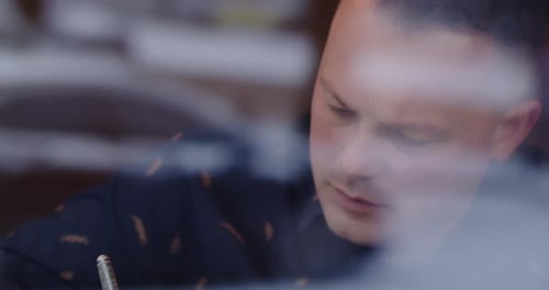 Focused Man Writes A Letter While Sitting In A Cafe