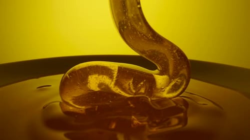 Honey Dripping Pouring Thick Stream on Yellow Background