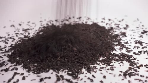 Close Up Of Dried Tea Leaves Falling On White Surface