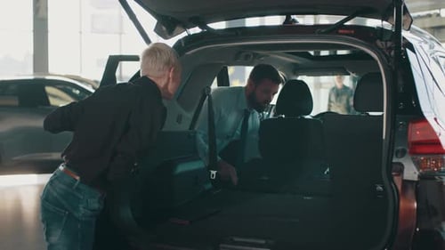 Car Salesman Showing Customer Car in Automotive Dealership Showroom