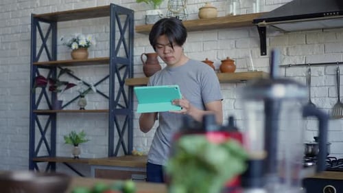 Young Adult Using Tablet in Kitchen