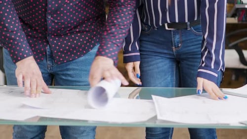 Close Up of Architects Hands Opening Blueprints in the Office