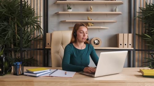 Woman working at laptop wearing a headset