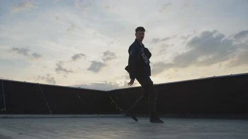 Young Dancer Performing Breakdancing on Rooftop at Sunset
