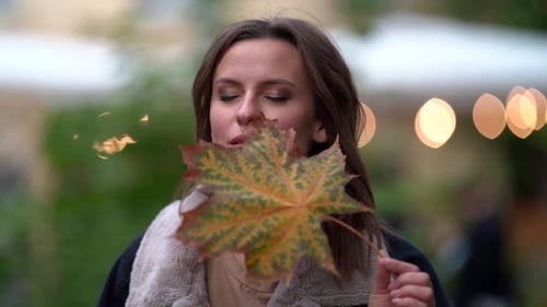 Woman Holds Colorful Fall Leaf to Her Face