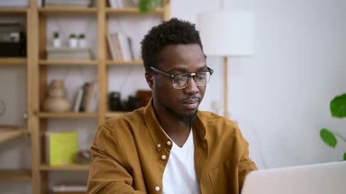 Young Adult Working on Laptop at Desk Indoors