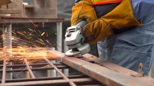 Welder man using angle grinder while working in industrial workshop. Sparks during the cutting