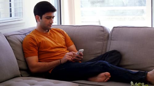 Man using mobile phone in living room 4k