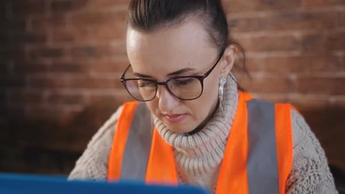 Focused Woman Builder Works with Laptop and with the Technical Documentation in the Room at the