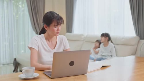 Woman Works on Laptop While Children Play