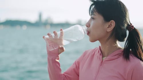 Woman Drinks Water After Exercise on Beach