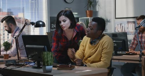 Woman Assists Young Adult on Computer in Office