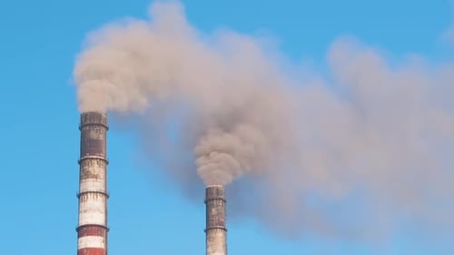 Nahaufnahme hoher Rohre eines Wärmekraftwerks mit schwarzem Rauch, der sich nach oben bewegt und die verschmutzende Atmosphäre schädigt