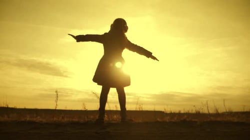 Silhouette Girl Child Stands in a Field at Sunset Wide Open Arms. The Concept of Childhood Dreams.
