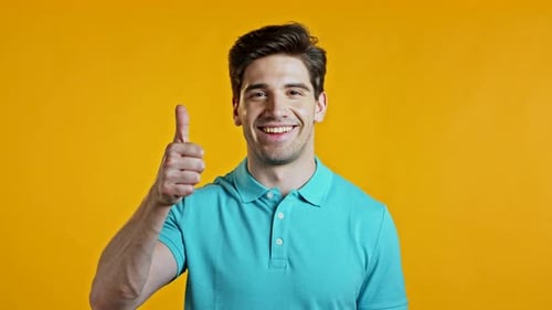 Handsome Young Man Smiles To Camera. Guy Showing Thumbs Up, Like Sign Over Yellow Background. Winner