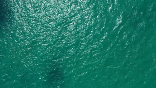 Dark turquoise sea texture of vibrant lagoon water reflecting sunny rays with coral reefs patterns o