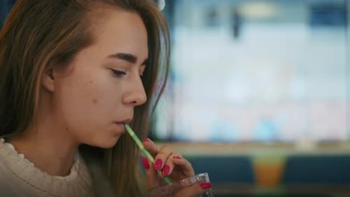 Joyful Girl Drinking Tea in a Cafe and Talking on the Phone or Video Call