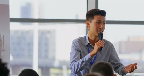 Man Speaks at Corporate Conference Using Microphone