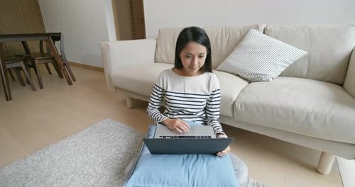 Woman Using Laptop on Pillow at Home