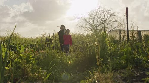 Three kids working in an organic vegetable garden weeding and watering plants