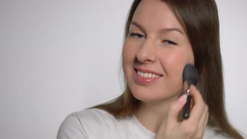 Woman Applying Makeup With Brush Indoors