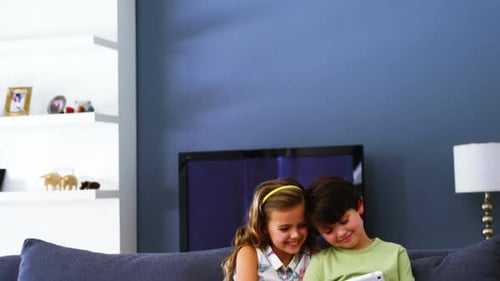 Boy and Girl Use Tablet on Couch