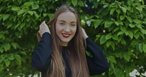 Portrait of Cheerful Young Woman in Park Against Trees