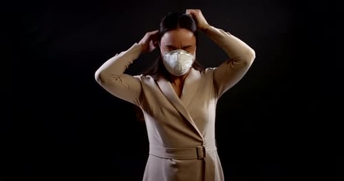 Woman Adjusting Surgical Mask Against Black Background