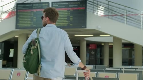 Young Adult Looks at Flight Information Board