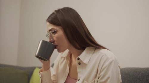 European Girl Sitting on the Couch Drinking Coffee and Writing