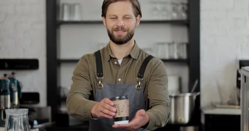 Friendly Barista Offers Coffee in Cafe