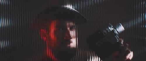 Man With Hat Holding Vintage Camera in Dark