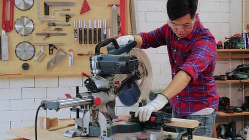 Young Adult Cutting Wood with Power Saw