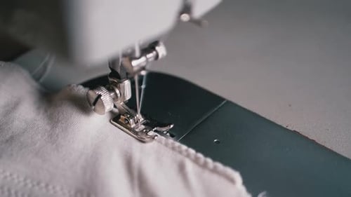 Close-up of Sewing Machine Needle with Thread Pierces Fabric in Slow Motion