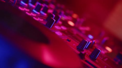 Hand Plugging Cord Into DJ Mixer At Night